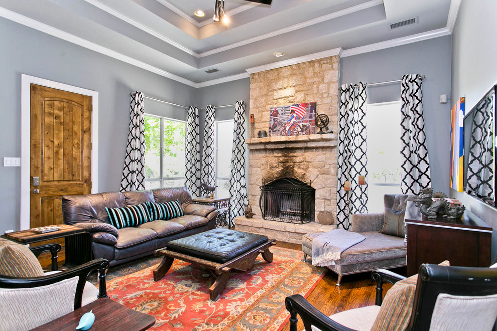 This is an example of a transitional enclosed family room in Dallas with grey walls, dark hardwood floors, a standard fireplace and a stone fireplace surround.