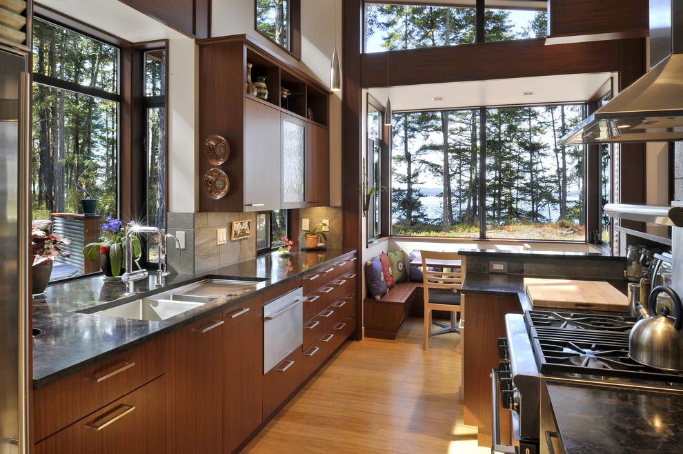 Inspiration for a contemporary galley eat-in kitchen in Seattle with a double-bowl sink, flat-panel cabinets, dark wood cabinets and stainless steel appliances.