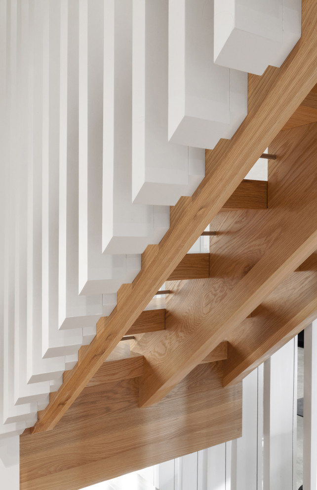 Inredning av en minimalistisk mellanstor l-trappa i trä, med öppna sättsteg och räcke i trä