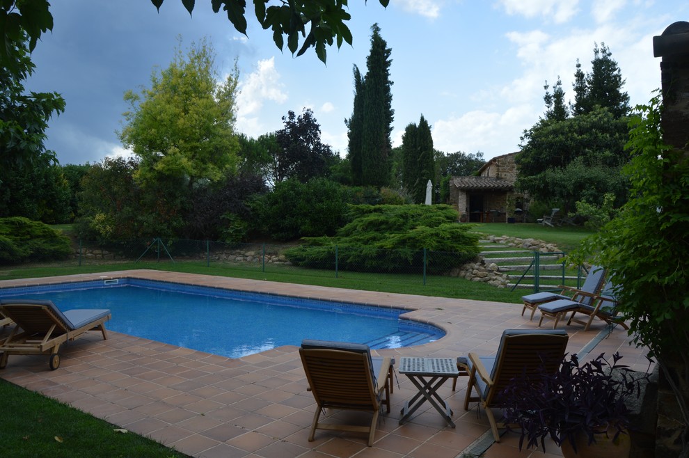 Country backyard rectangular pool in Barcelona with a pool house and tile.