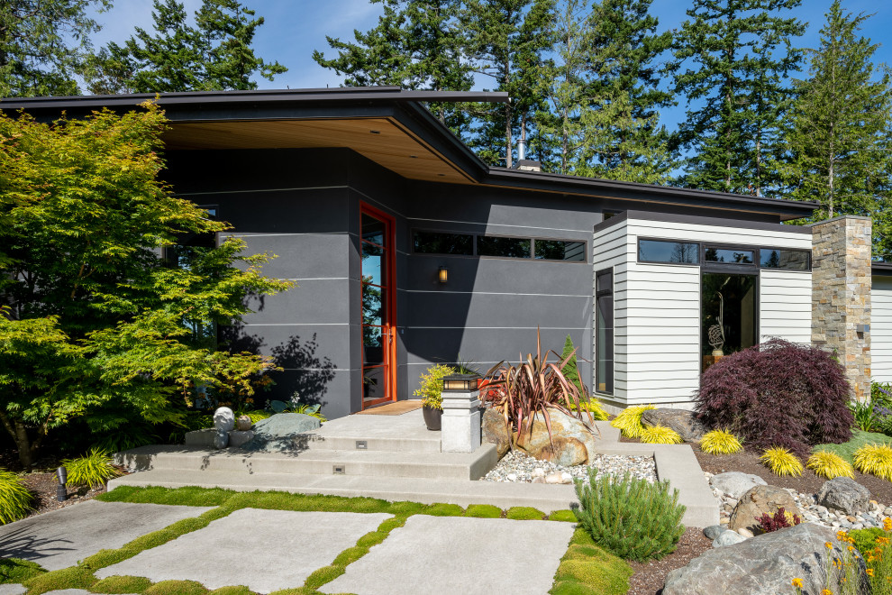 Réalisation d'une façade de maison multicolore minimaliste en bardage à clin de taille moyenne et de plain-pied avec un revêtement mixte, un toit en appentis, un toit en métal et un toit noir.