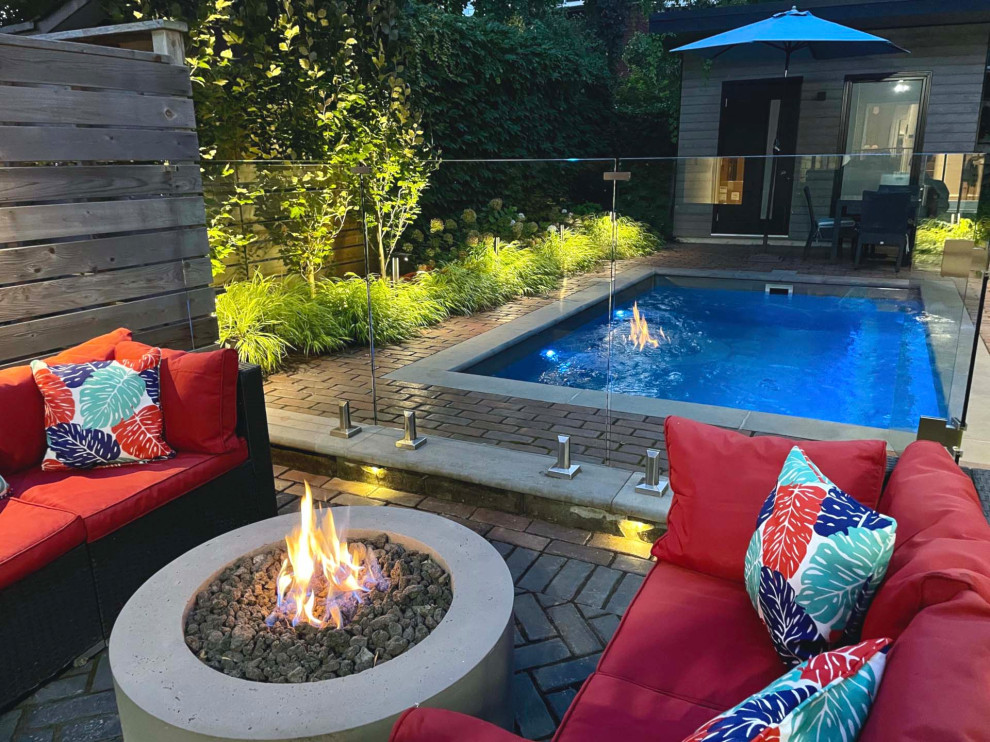 Inspiration for a mid-sized eclectic full sun backyard concrete paver and wood fence landscaping in Toronto with a fire pit.