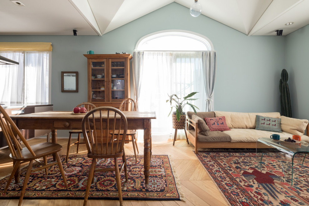 Immagine di una sala da pranzo aperta verso il soggiorno stile rurale di medie dimensioni con pareti blu, parquet chiaro, pavimento beige e carta da parati