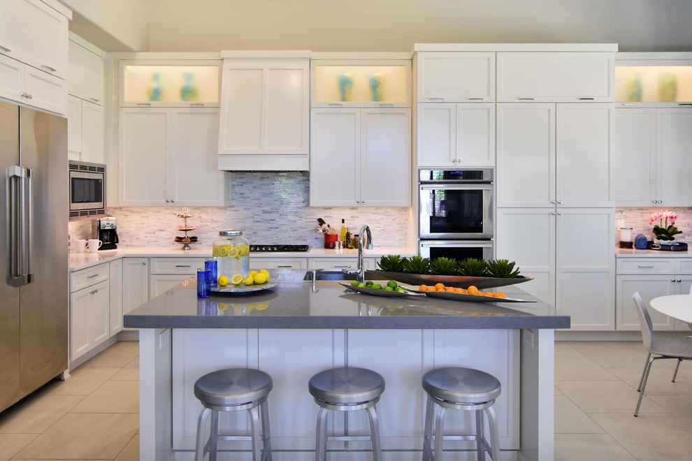 Large transitional u-shaped eat-in kitchen in Phoenix with an undermount sink, recessed-panel cabinets, white cabinets, quartz benchtops, white splashback, stone tile splashback, stainless steel appliances, porcelain floors, with island, beige floor and grey benchtop.