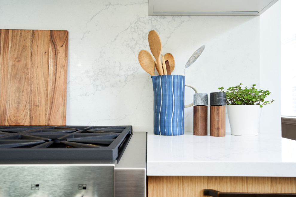 Bild på ett mellanstort funkis vit vitt kök, med en rustik diskho, släta luckor, skåp i ljust trä, bänkskiva i kvartsit, grönt stänkskydd, stänkskydd i keramik, rostfria vitvaror, ljust trägolv och en köksö