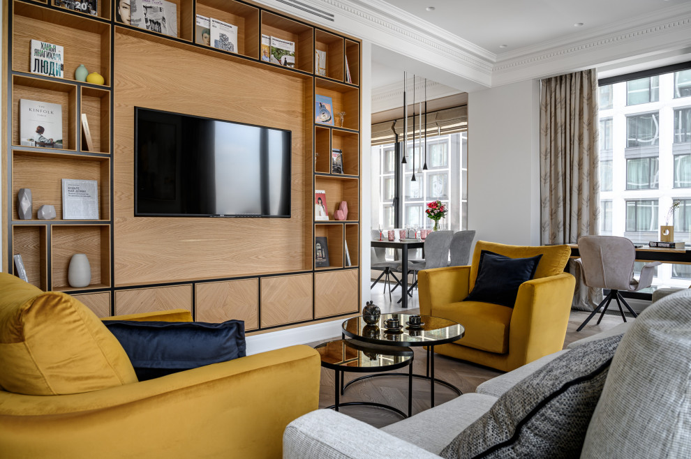 На фото: гостиная комната в современном стиле с серыми стенами, паркетным полом среднего тона, телевизором на стене и коричневым полом с