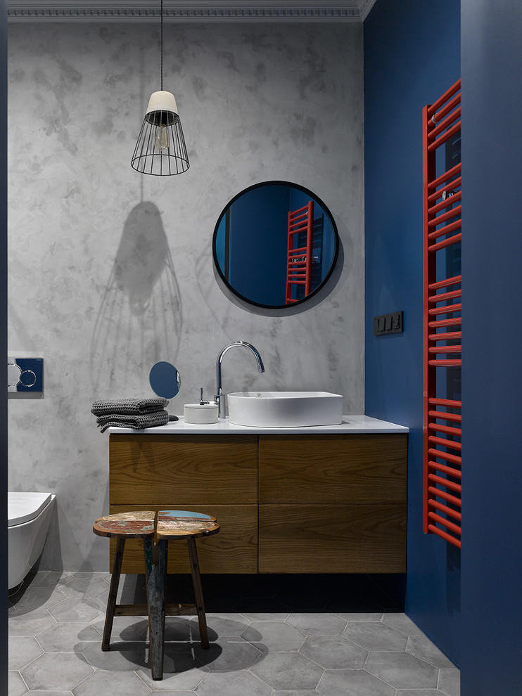 Photo of a contemporary bathroom in Moscow with flat-panel cabinets, dark wood cabinets, a wall-mount toilet, blue walls, a vessel sink, grey floor and white benchtops.