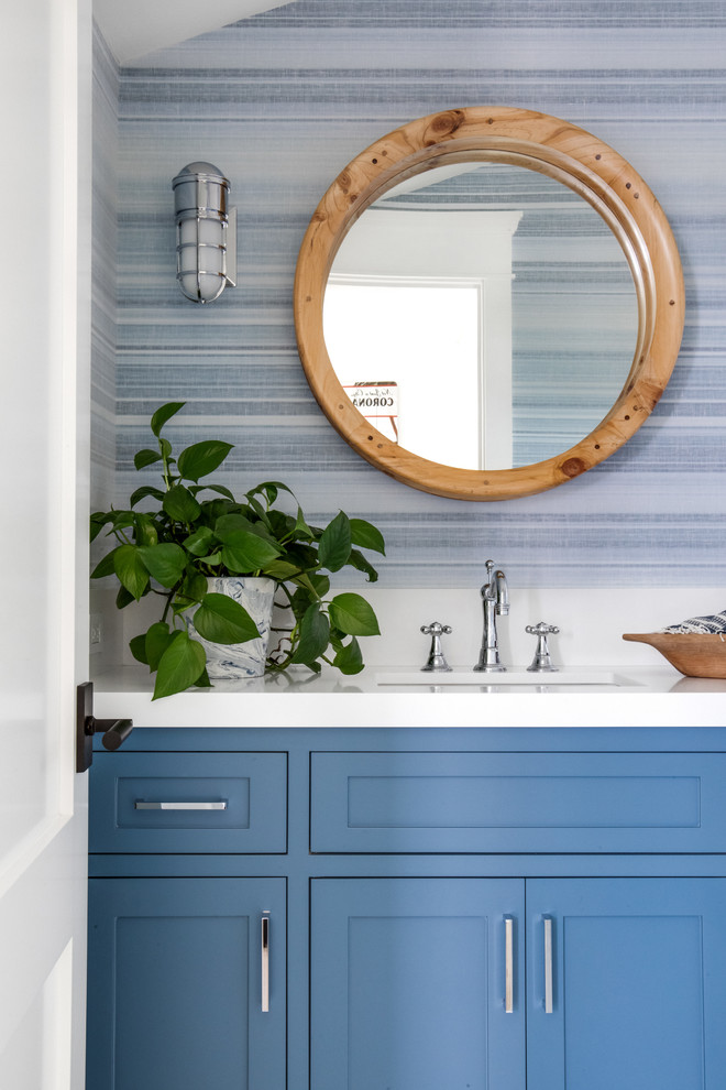 This is an example of a beach style bathroom in Los Angeles with shaker cabinets, blue cabinets, blue walls, an undermount sink and white benchtops.