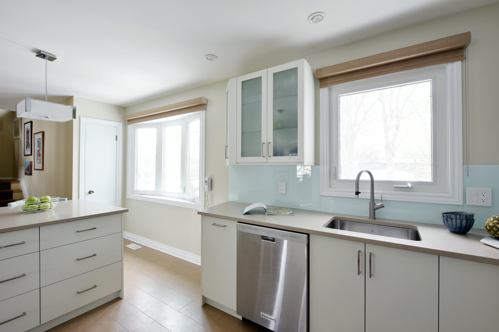 Inspiration for a mid-sized transitional u-shaped cork floor enclosed kitchen remodel in Ottawa with an undermount sink, flat-panel cabinets, white cabinets, quartz countertops, blue backsplash, glass sheet backsplash, stainless steel appliances and an island