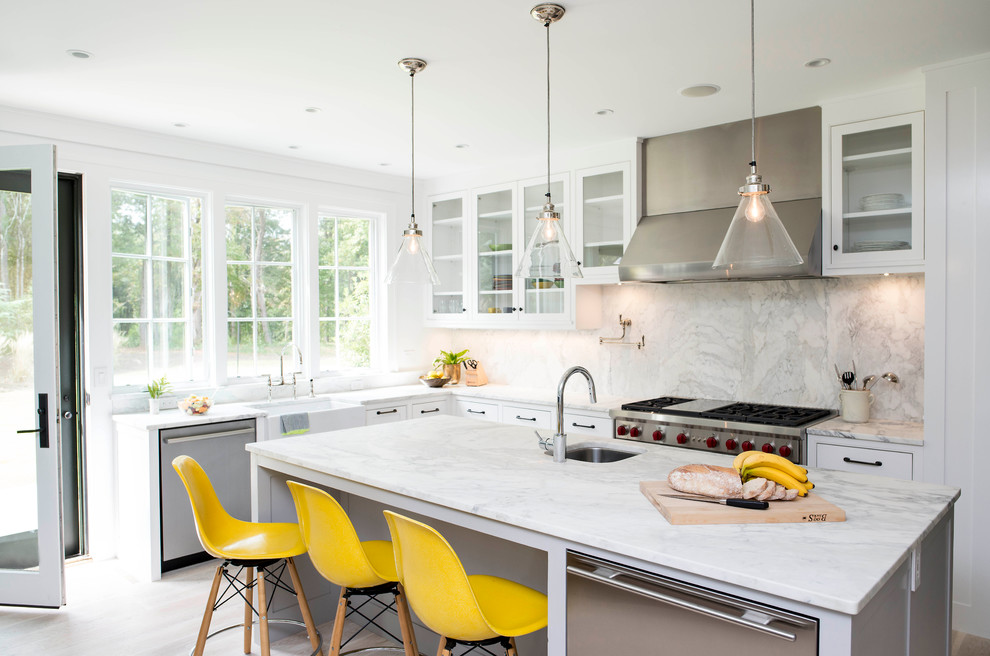 Design ideas for a transitional l-shaped open plan kitchen in Raleigh with a farmhouse sink, glass-front cabinets, white cabinets, marble benchtops, white splashback, stone slab splashback, stainless steel appliances and with island.