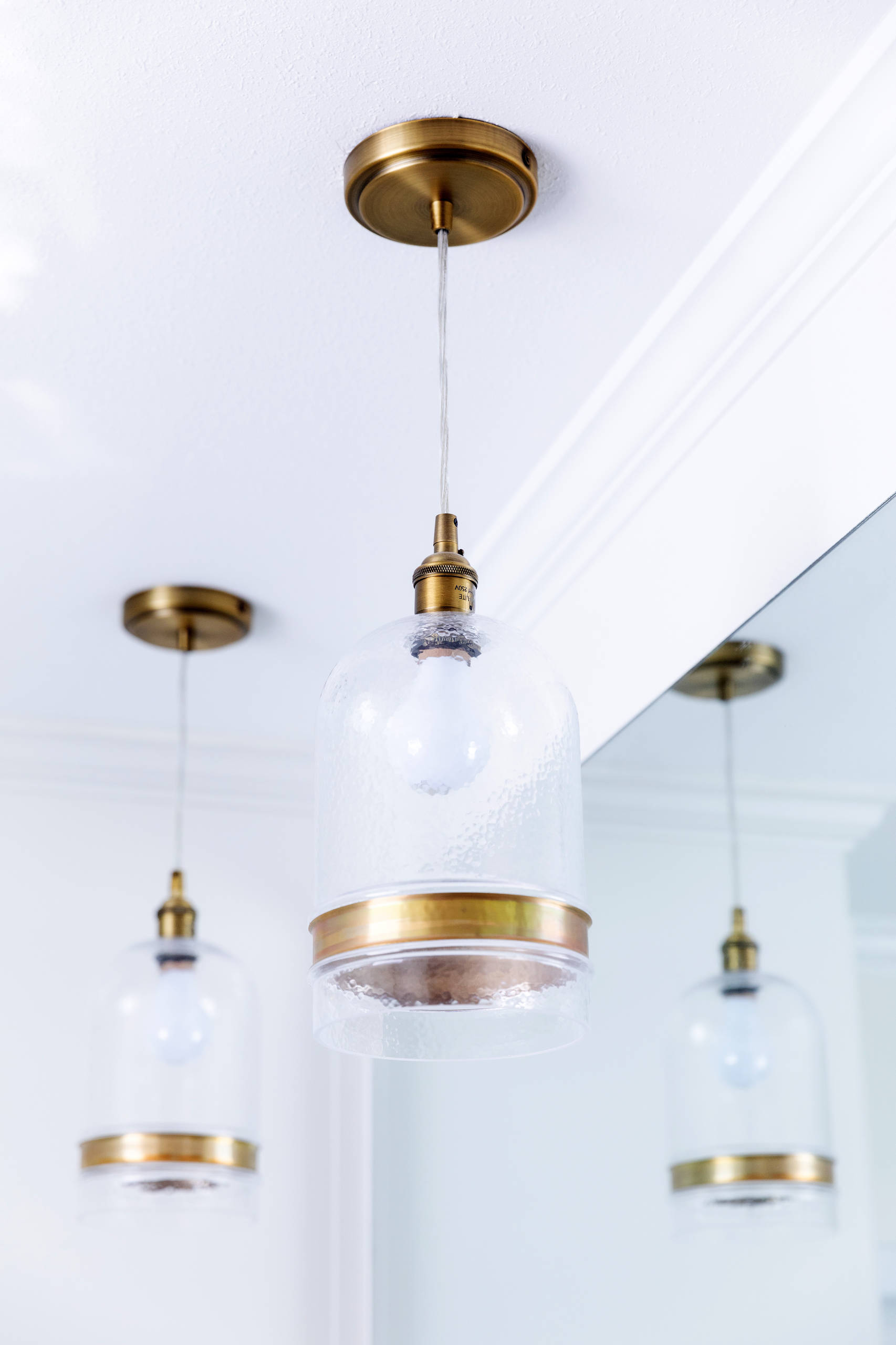 Close up of glass pendant lights with antique copper accents used above the vanities. Space Planning by Ourso Designs. Photo by Collin Richie (Collin Richie Photography).