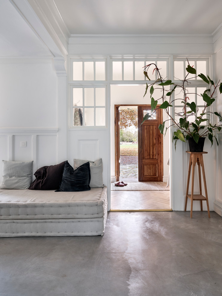 Large scandinavian entryway in Malmo with white walls and concrete floors.