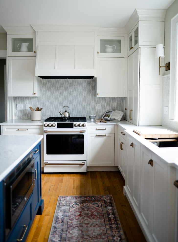 Inspiration for a mid-sized traditional eat-in kitchen in Portland Maine with an undermount sink, flat-panel cabinets, white cabinets, quartz benchtops, coloured appliances, light hardwood floors, with island and white benchtop.
