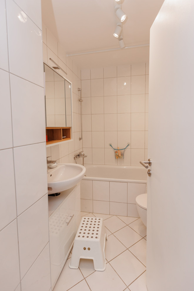 Kleines Modernes Badezimmer mit weißen Schränken, Duschbadewanne, weißen Fliesen, weißer Wandfarbe und Einzelwaschbecken in Frankfurt am Main