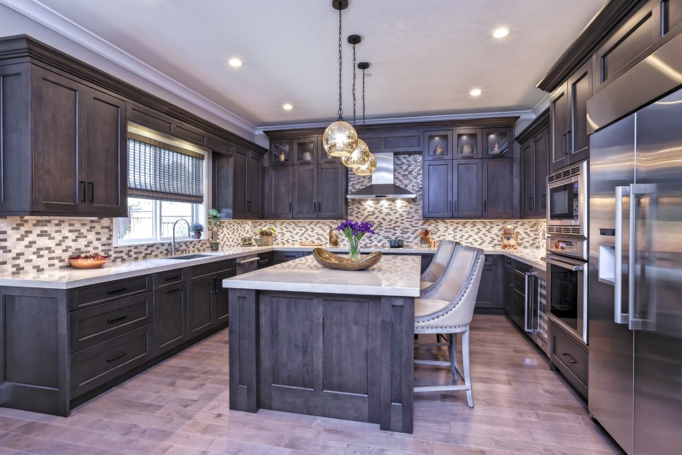 Eat-in kitchen - large transitional u-shaped medium tone wood floor and brown floor eat-in kitchen idea with an undermount sink, recessed-panel cabinets, brown cabinets, marble countertops, multicolored backsplash, porcelain backsplash, stainless steel appliances and an island