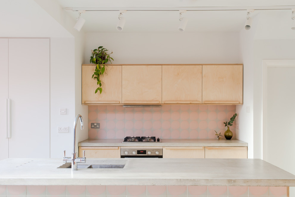 Design ideas for a mid-sized scandinavian galley eat-in kitchen in London with flat-panel cabinets, medium wood cabinets, concrete benchtops, pink splashback, ceramic splashback, panelled appliances, concrete floors, with island, green floor and grey benchtop.