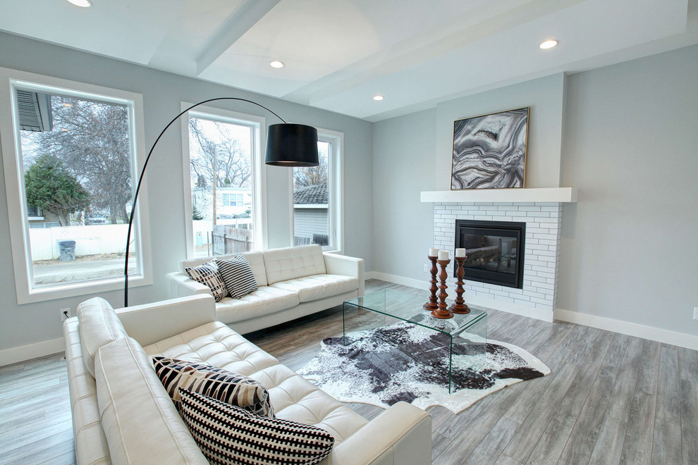 This is an example of a large modern formal open concept living room in Calgary with grey walls, laminate floors, a standard fireplace, a tile fireplace surround and no tv.