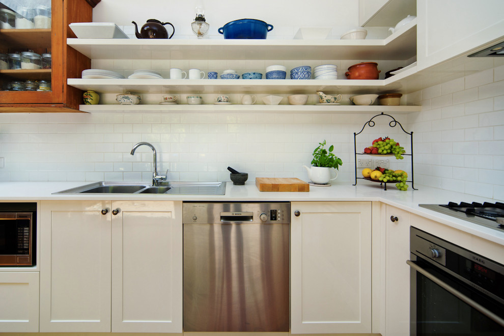 Photo of a mid-sized country l-shaped eat-in kitchen in Sydney with shaker cabinets, white splashback, ceramic splashback, stainless steel appliances, medium hardwood floors and with island.