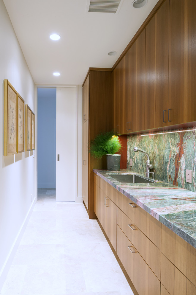 Photo of a large contemporary galley kitchen pantry in Hawaii with flat-panel cabinets, medium wood cabinets, granite benchtops, green splashback, stone slab splashback, travertine floors, with island, an undermount sink and panelled appliances.