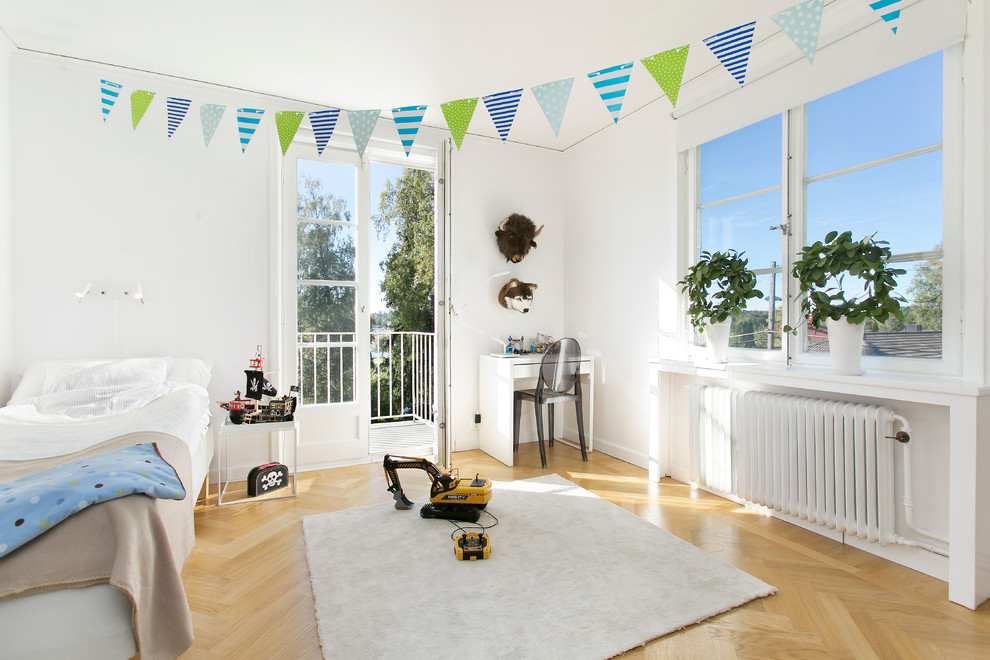This is an example of a large modern gender-neutral kids' bedroom for kids 4-10 years old in Stockholm with white walls and medium hardwood floors.
