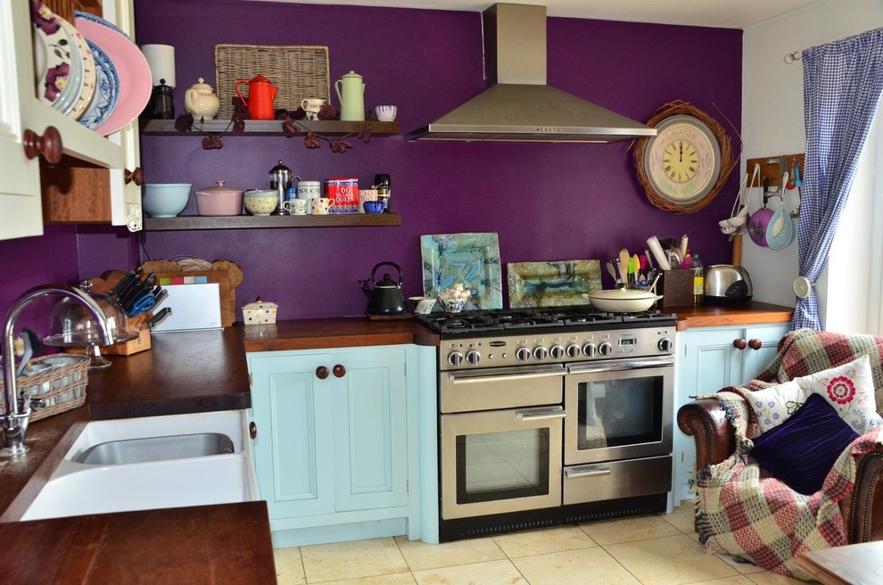 Photo of a mid-sized country l-shaped eat-in kitchen in Wiltshire with a drop-in sink, shaker cabinets, blue cabinets, wood benchtops, stainless steel appliances, ceramic floors, no island and beige floor.