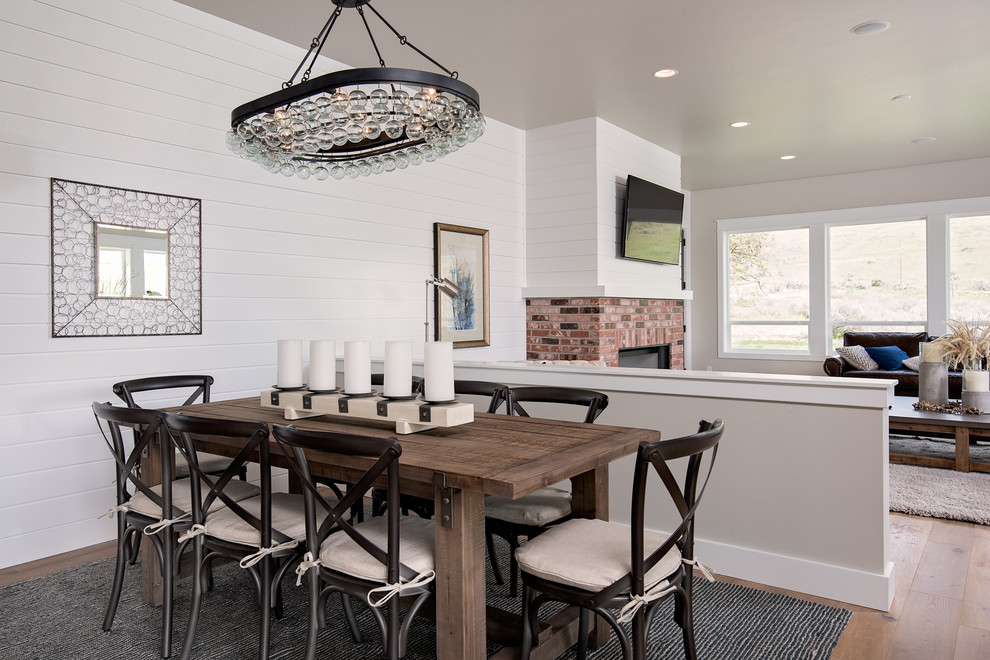 Inspiration for a country open plan dining in Boise with grey walls, light hardwood floors, a standard fireplace and a brick fireplace surround.