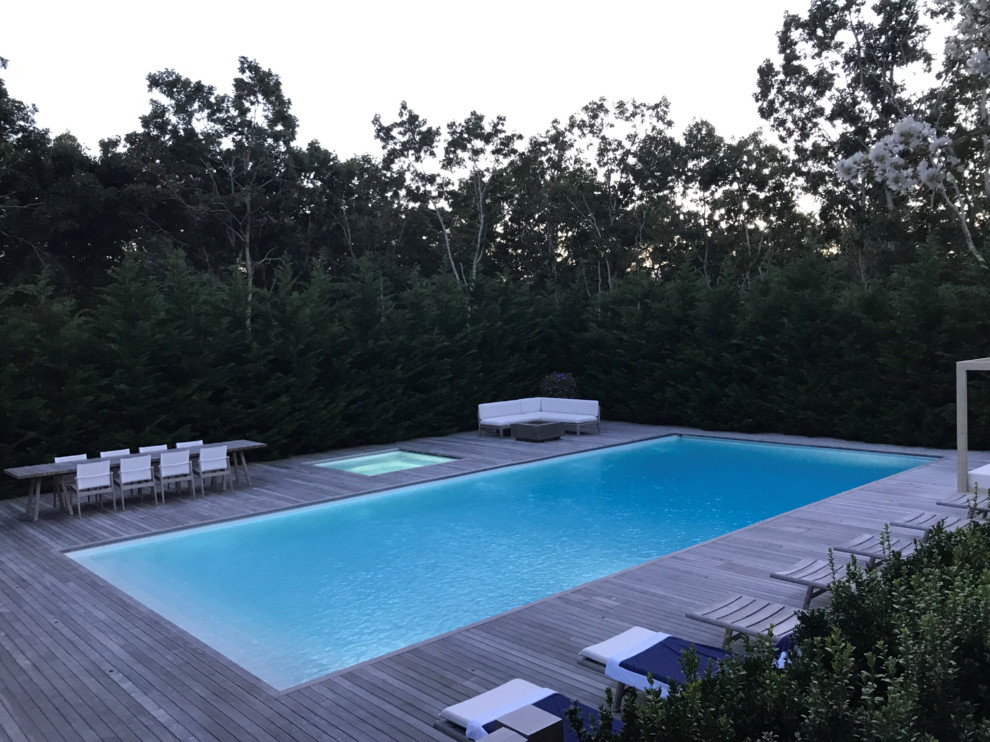 Large contemporary courtyard custom-shaped lap pool in New York with a hot tub and decking.