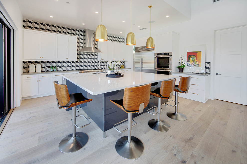 Large contemporary kitchen in Orange County with an undermount sink, shaker cabinets, white cabinets, quartz benchtops, cement tile splashback, stainless steel appliances, light hardwood floors, with island and multi-coloured splashback.