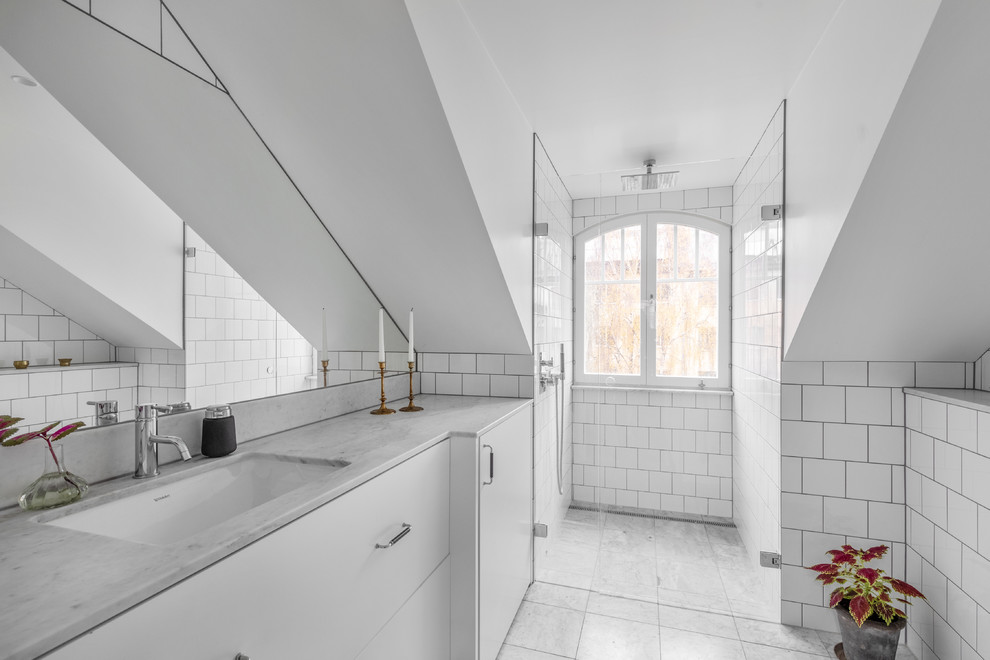 Inspiration for a scandinavian 3/4 bathroom in Stockholm with flat-panel cabinets, white cabinets, a curbless shower, white tile, white walls, marble floors, an undermount sink, marble benchtops, grey floor, a hinged shower door and grey benchtops.