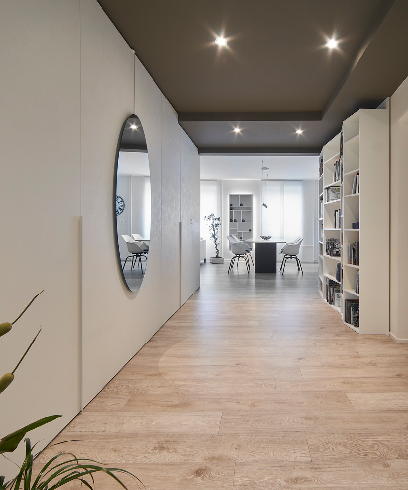 Стильный дизайн: коридор среднего размера в современном стиле с белыми стенами, светлым паркетным полом, многоуровневым потолком и панелями на стенах - последний тренд