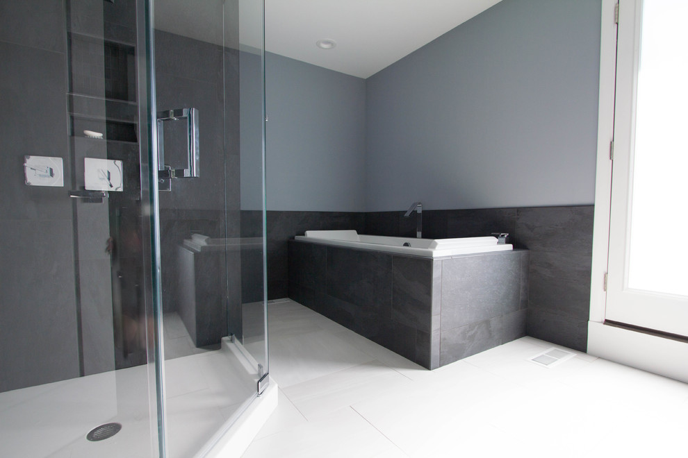This is an example of a mid-sized modern master bathroom in Philadelphia with flat-panel cabinets, black cabinets, a drop-in tub, a corner shower, black tile, porcelain tile, grey walls, porcelain floors, an integrated sink, solid surface benchtops, white floor and a hinged shower door.