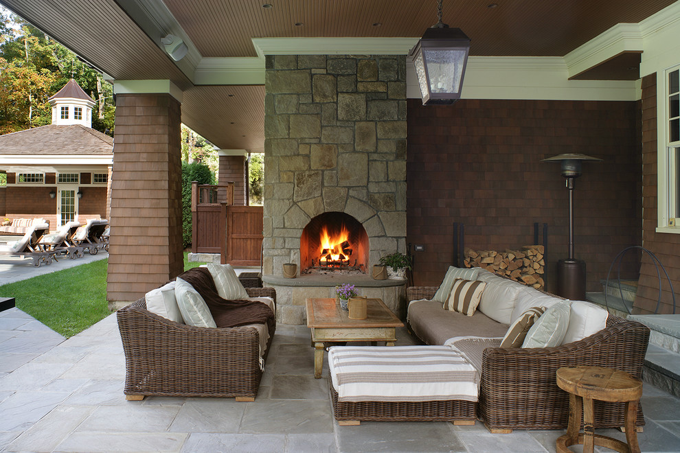 Design ideas for a large traditional backyard patio in New York with a fire feature, natural stone pavers and a roof extension.