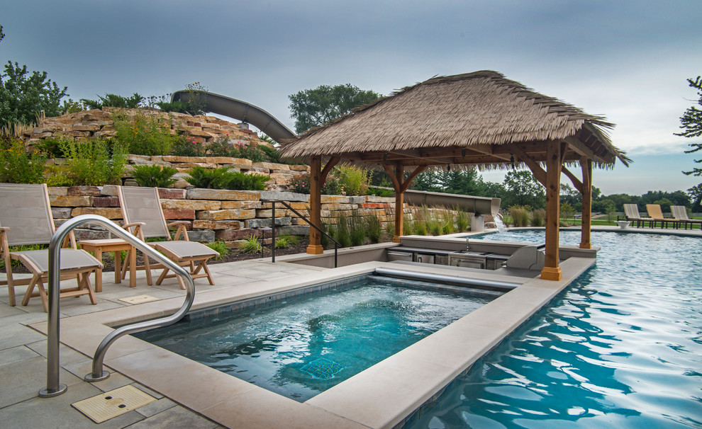 Inspiration for an expansive tropical backyard custom-shaped lap pool in Chicago with a water slide and natural stone pavers.