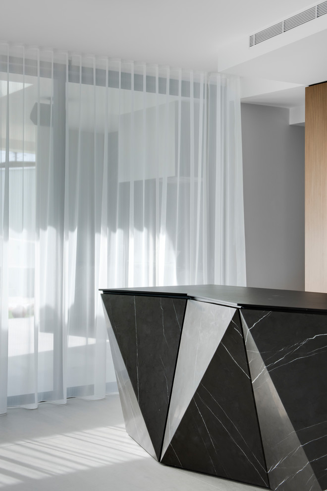 Large contemporary galley kitchen pantry in Sydney with a double-bowl sink, flat-panel cabinets, white cabinets, recycled glass benchtops, grey splashback, marble splashback, black appliances, porcelain floors, with island, grey floor and black benchtop.