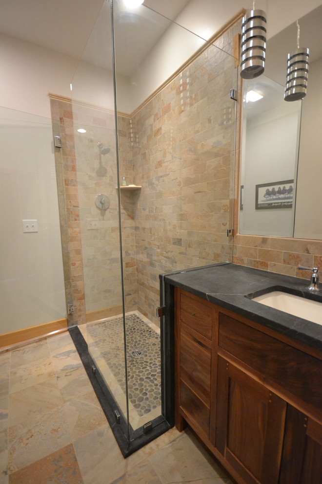 Inspiration for a mid-sized rustic beige tile and brown tile slate floor and brown floor alcove shower remodel with shaker cabinets, dark wood cabinets, brown walls, an undermount sink, soapstone countertops and a hinged shower door