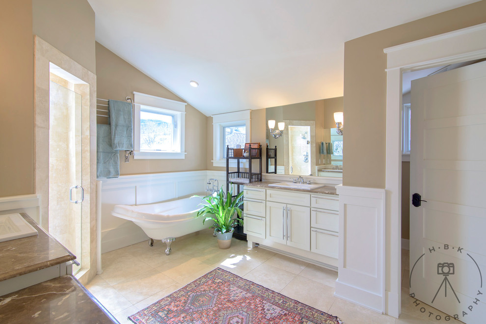 Photo of a mid-sized master bathroom with recessed-panel cabinets, white cabinets, a claw-foot tub, a corner shower, beige walls, a drop-in sink, beige floor, a hinged shower door and beige benchtops.