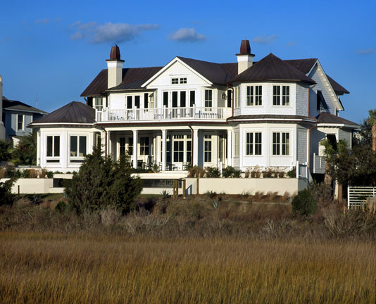 Photo of an expansive beach style two-storey house exterior in Charleston with wood siding and a metal roof.