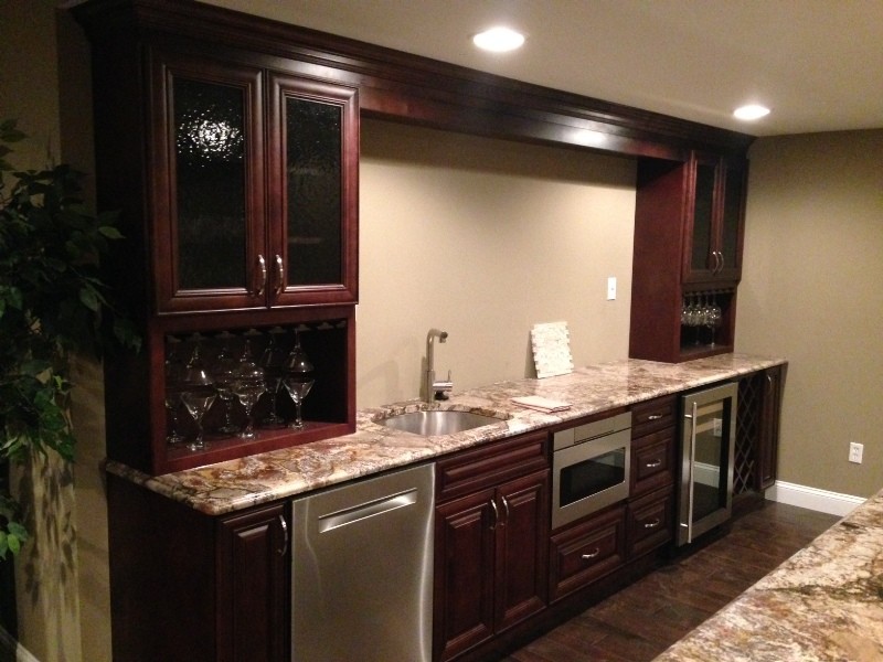 Design ideas for a mid-sized traditional galley wet bar in St Louis with an undermount sink, raised-panel cabinets, brown cabinets, granite benchtops and porcelain floors.
