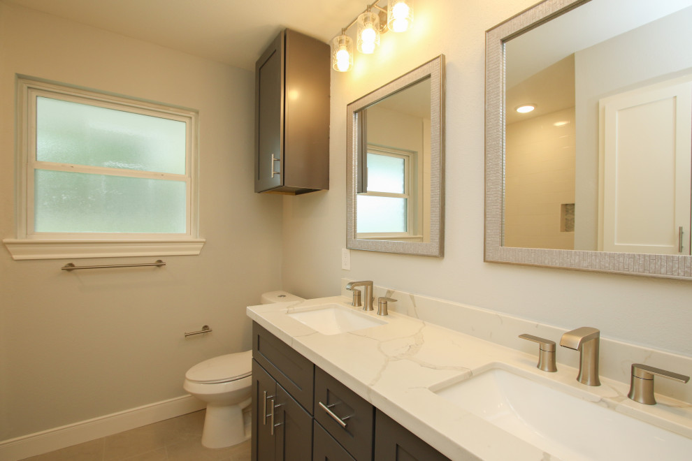 Medium sized classic family bathroom in Houston with shaker cabinets, grey cabinets, an alcove bath, a shower/bath combination, a two-piece toilet, grey walls, porcelain flooring, a submerged sink, engineered stone worktops, grey floors, an open shower, white worktops, a wall niche, double sinks and a built in vanity unit.