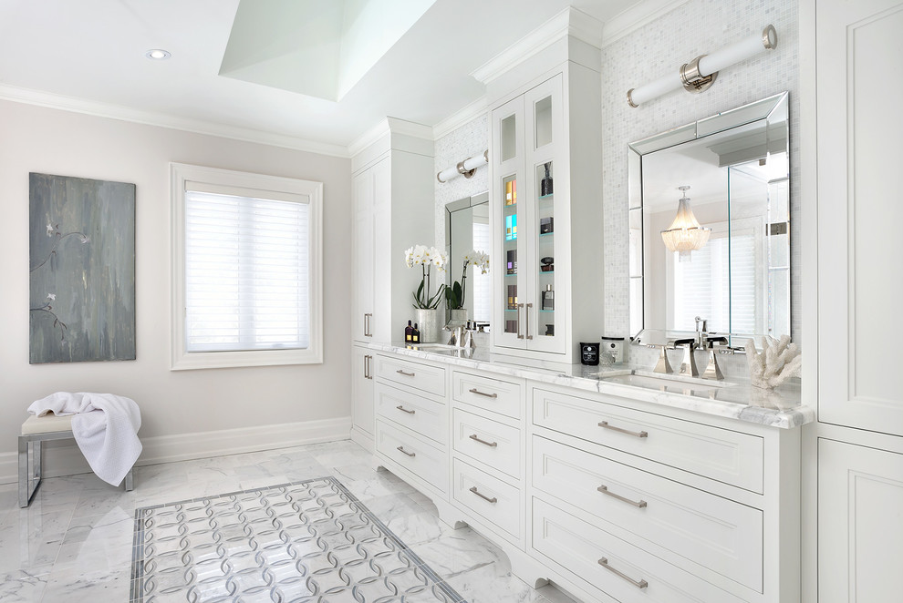 Photo of a large transitional master bathroom in Toronto with white cabinets, a freestanding tub, a corner shower, white tile, stone tile, white walls, marble floors, an undermount sink, marble benchtops and recessed-panel cabinets.