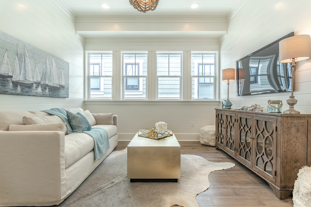 Inspiration for a mid-sized beach style open concept family room in Other with white walls, medium hardwood floors, a wall-mounted tv, brown floor and no fireplace.