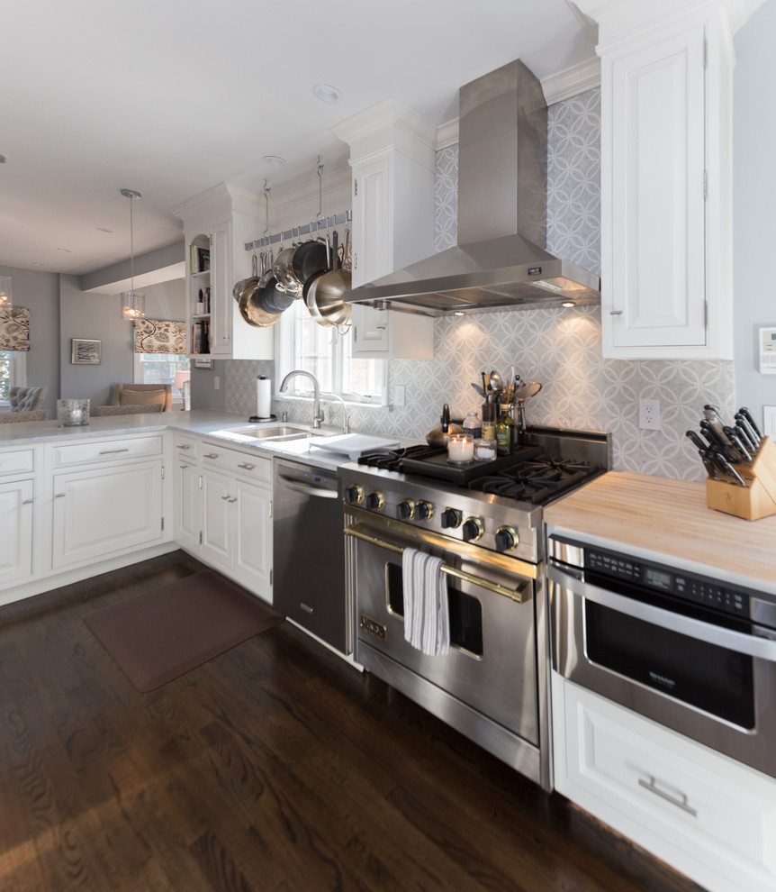 This is an example of a large contemporary l-shaped eat-in kitchen in New York with an undermount sink, raised-panel cabinets, white cabinets, granite benchtops, grey splashback, ceramic splashback, stainless steel appliances, dark hardwood floors and brown floor.