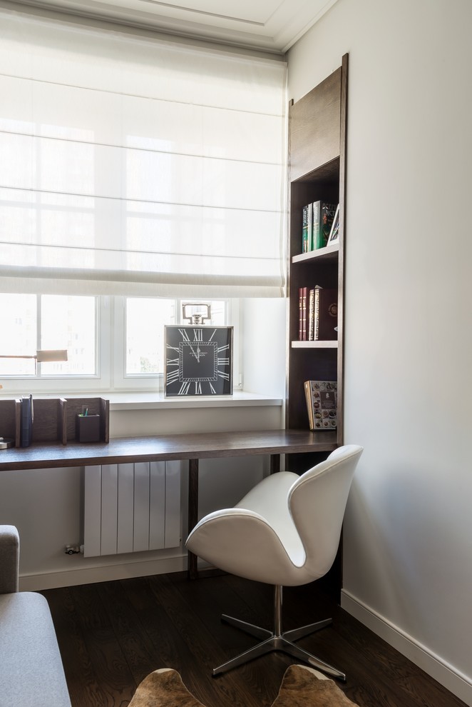 This is an example of a contemporary study room in Moscow with white walls, dark hardwood floors and a built-in desk.
