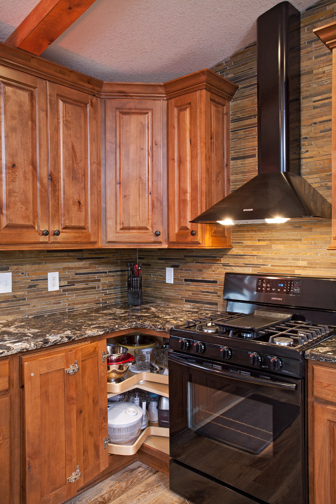 Inspiration for a mid-sized rustic l-shaped light wood floor eat-in kitchen remodel in Minneapolis with an undermount sink, raised-panel cabinets, medium tone wood cabinets, quartz countertops, green backsplash, stone tile backsplash, black appliances and an island