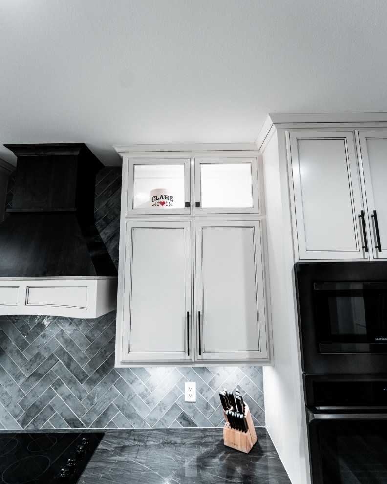 Open concept kitchen - huge transitional l-shaped laminate floor, gray floor and tray ceiling open concept kitchen idea with an undermount sink, flat-panel cabinets, white cabinets, quartz countertops, gray backsplash, ceramic backsplash, black appliances and an island