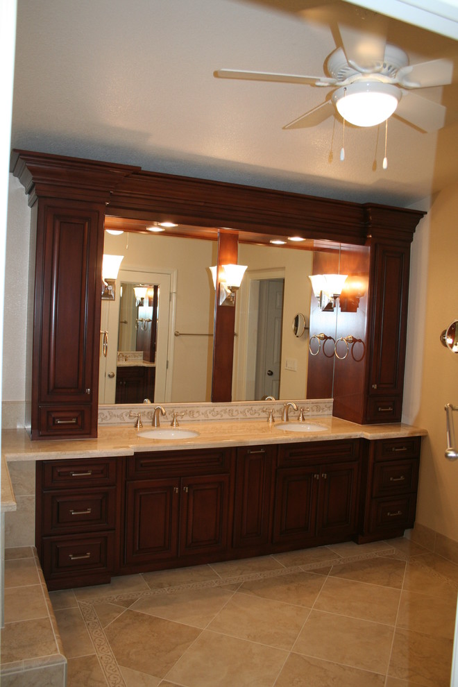 Photo of a mid-sized traditional master bathroom in Orange County with raised-panel cabinets, dark wood cabinets, a drop-in tub, an alcove shower, beige tile, beige walls, limestone floors, an undermount sink and granite benchtops.