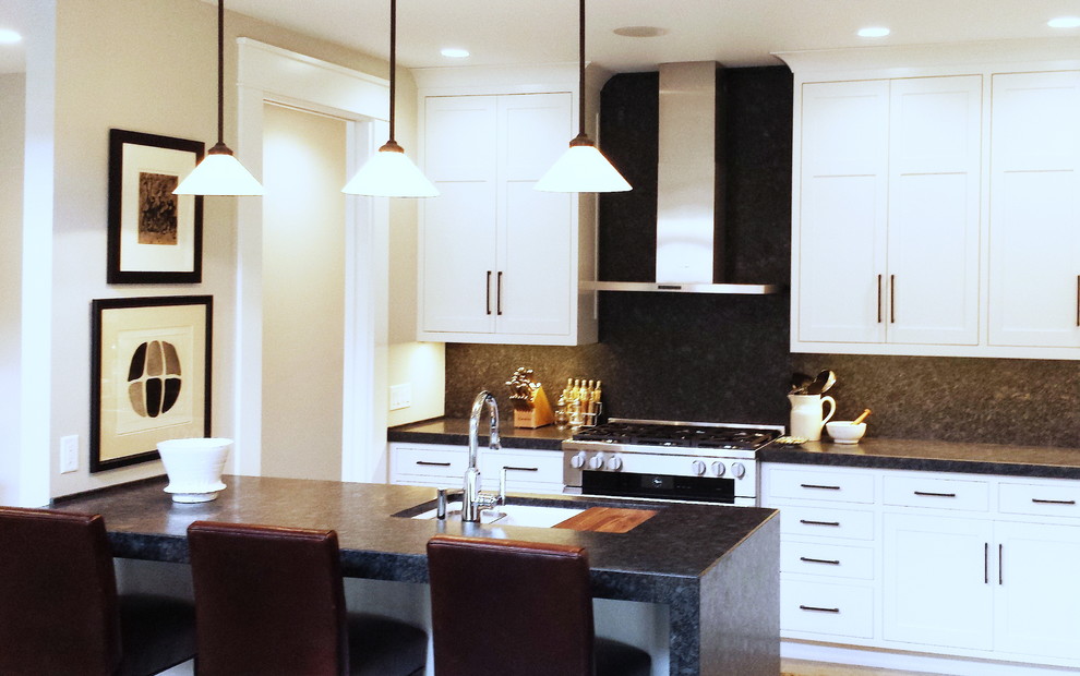 Mid-sized transitional l-shaped concrete floor and beige floor eat-in kitchen photo with an undermount sink, shaker cabinets, white cabinets, granite countertops, black backsplash, stone slab backsplash, paneled appliances and a peninsula