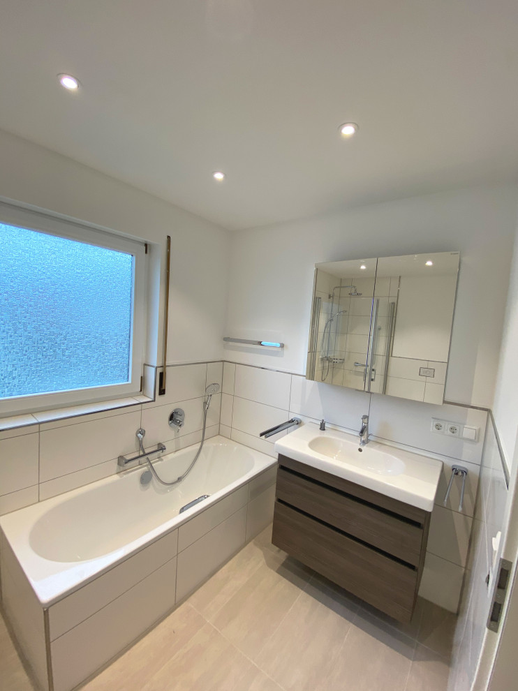 This is an example of a small contemporary 3/4 bathroom in Other with flat-panel cabinets, dark wood cabinets, a drop-in tub, a curbless shower, a wall-mount toilet, white tile, porcelain tile, white walls, porcelain floors, a drop-in sink, wood benchtops, beige floor, a hinged shower door, white benchtops, a single vanity and a built-in vanity.