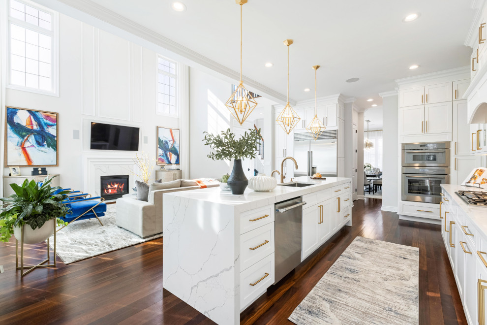 Example of a large classic single-wall medium tone wood floor and brown floor open concept kitchen design in New York with an undermount sink, shaker cabinets, white cabinets, quartz countertops, white backsplash, quartz backsplash, paneled appliances, an island and white countertops