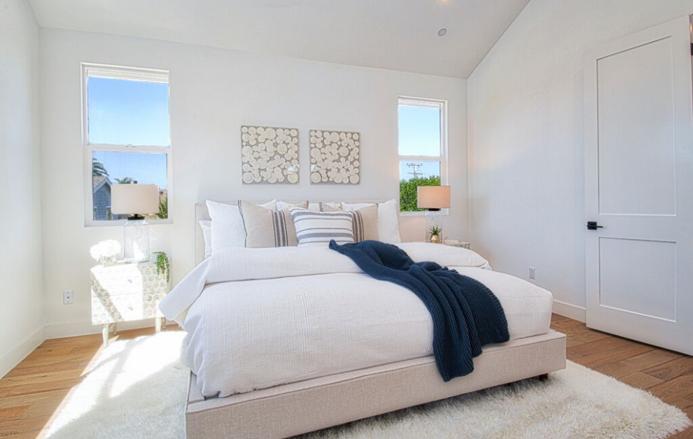 This is an example of a medium sized contemporary master bedroom in Orange County with light hardwood flooring.